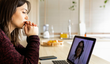 Person sat at a desk using a laptop for an online virtual consultation